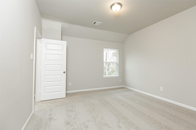 empty room with visible vents, carpet flooring, lofted ceiling, and baseboards