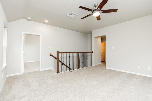 carpeted empty room featuring visible vents, baseboards, and vaulted ceiling