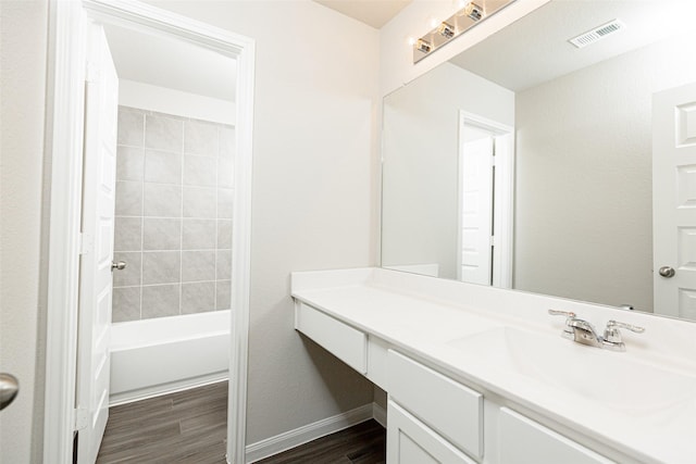 bathroom featuring visible vents, wood finished floors, shower / bathing tub combination, baseboards, and vanity