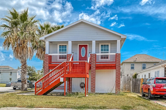 view of front of property with brick siding, fence, a porch, stairs, and a front yard