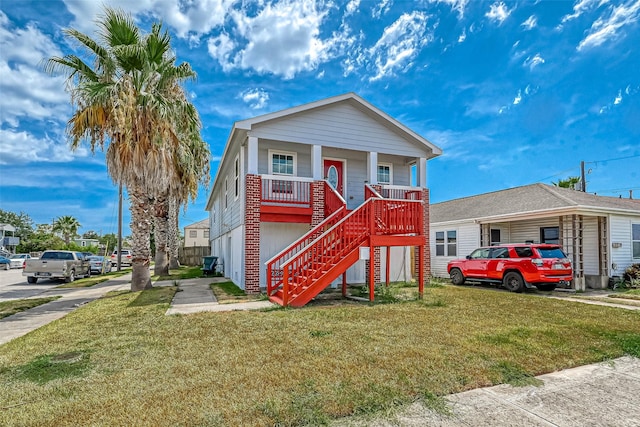 view of front facade with stairway, covered porch, and a front lawn