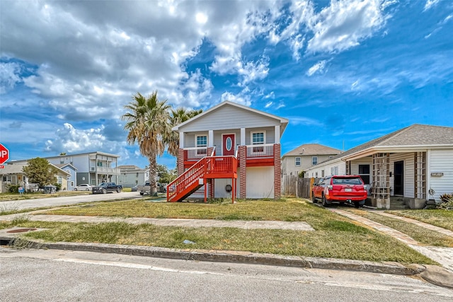 view of front of home with a front yard, stairway, covered porch, and a residential view