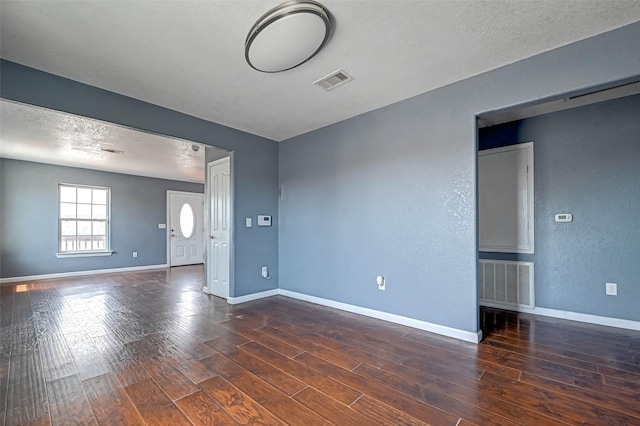 empty room with visible vents, baseboards, a textured ceiling, and wood finished floors