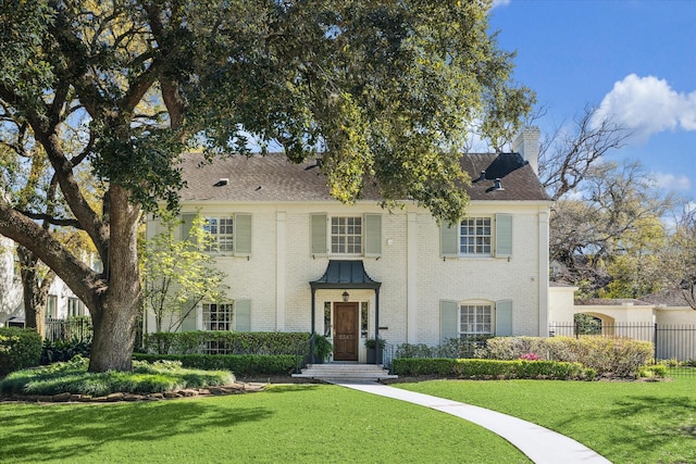 view of front facade with a front lawn, fence, and brick siding