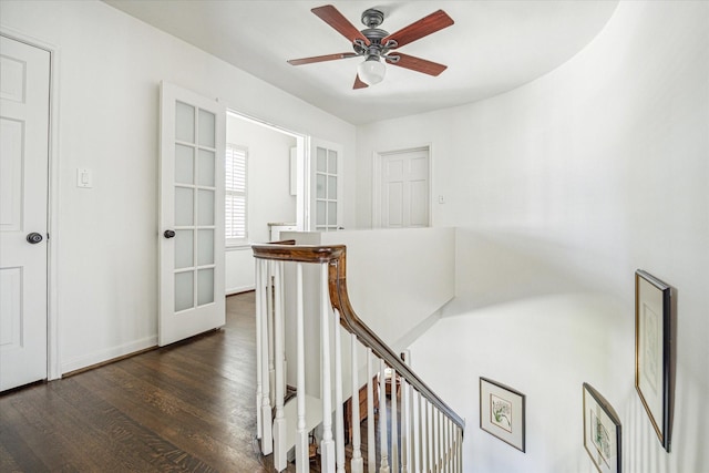 corridor featuring an upstairs landing, dark wood-type flooring, and baseboards