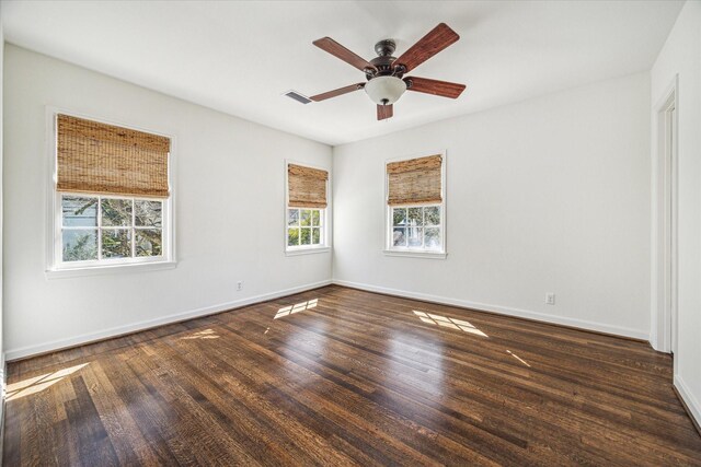 spare room with ceiling fan, visible vents, baseboards, and wood finished floors