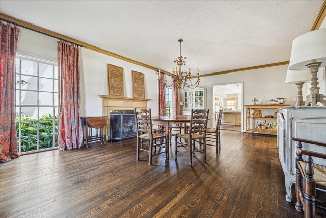 dining area featuring wood finished floors, a fireplace, ornamental molding, a textured ceiling, and a notable chandelier