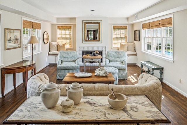 living area with dark wood finished floors, a brick fireplace, visible vents, and baseboards