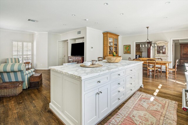 kitchen featuring visible vents, dark wood-type flooring, a center island, white cabinets, and crown molding