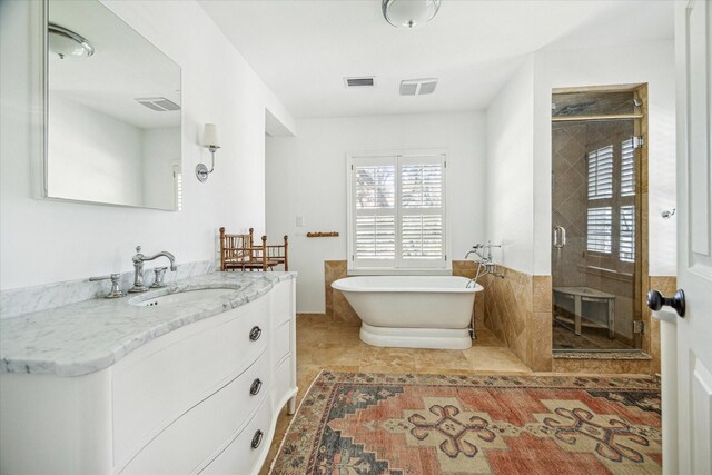 full bath with visible vents, a shower stall, vanity, and a freestanding tub