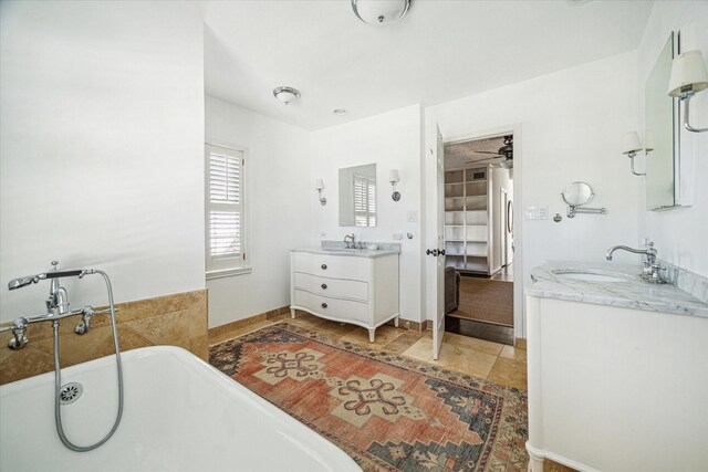 full bath with a freestanding tub, two vanities, baseboards, and a sink