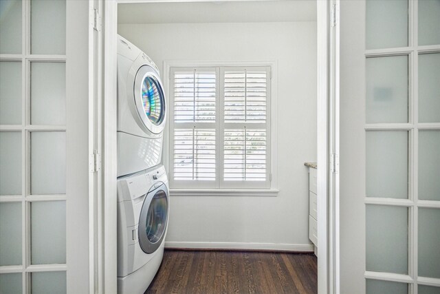 laundry area featuring stacked washer / dryer, laundry area, baseboards, and dark wood-style flooring