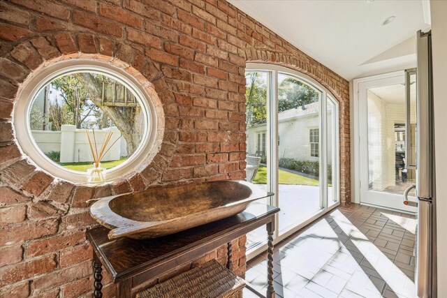 interior space featuring vaulted ceiling, brick wall, and a sink