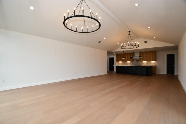 unfurnished living room featuring visible vents, baseboards, a chandelier, light wood-type flooring, and high vaulted ceiling