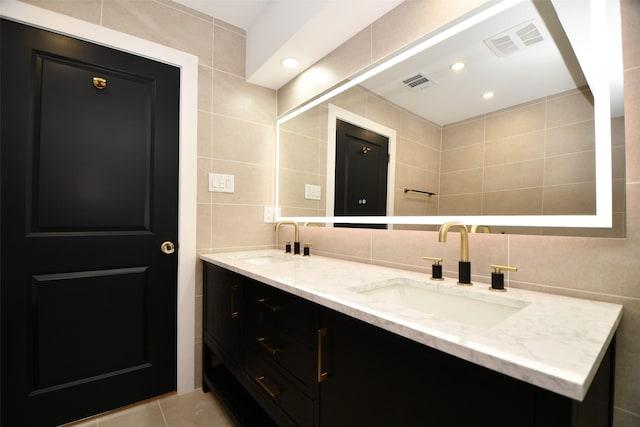 bathroom featuring tile walls, visible vents, and a sink