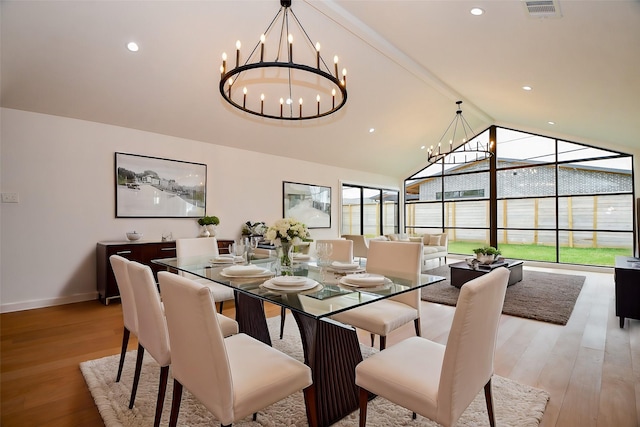 dining area featuring baseboards, visible vents, lofted ceiling, light wood-style flooring, and a notable chandelier