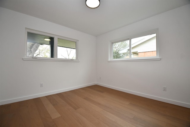 spare room featuring baseboards and light wood-type flooring