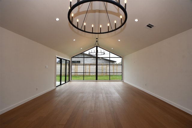 unfurnished living room featuring wood finished floors, baseboards, visible vents, and lofted ceiling