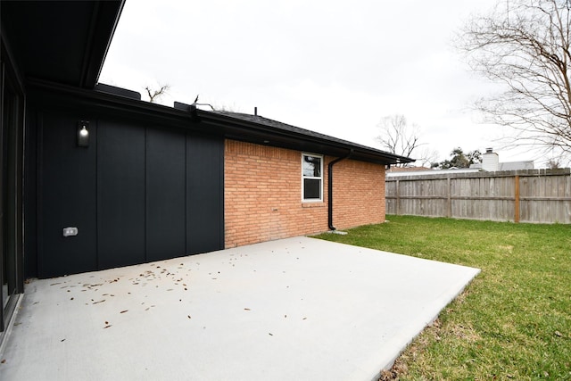 exterior space featuring a yard, brick siding, a patio area, and fence