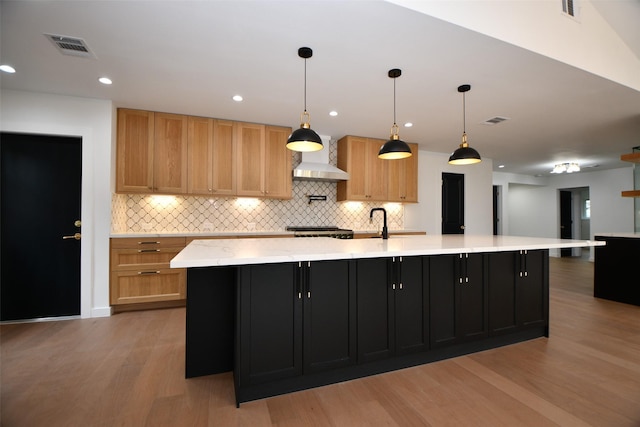 kitchen with visible vents, a large island, decorative backsplash, and light wood finished floors