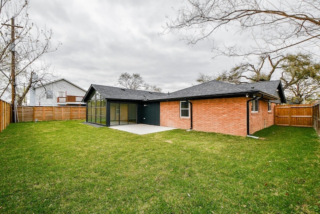 rear view of house featuring a lawn, a fenced backyard, roof with shingles, brick siding, and a patio area