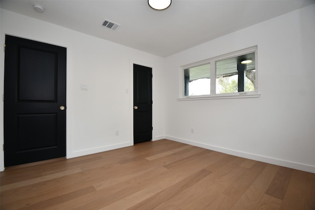 unfurnished room featuring light wood-style flooring, baseboards, and visible vents