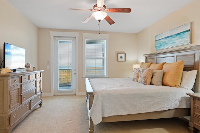 bedroom with access to exterior, light colored carpet, a ceiling fan, and baseboards