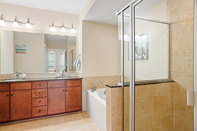 bathroom featuring tile patterned flooring, a bath, a stall shower, and a sink