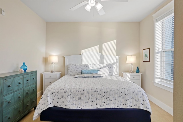 bedroom featuring baseboards, light colored carpet, and a ceiling fan