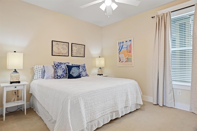 bedroom with a ceiling fan, baseboards, and light carpet