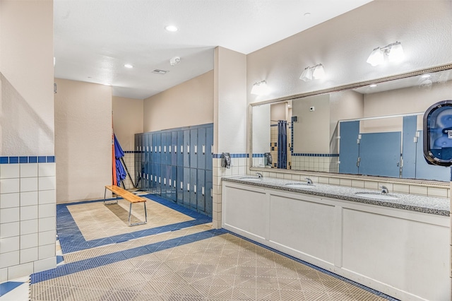 bathroom with tile walls, double vanity, tile patterned floors, and a sink