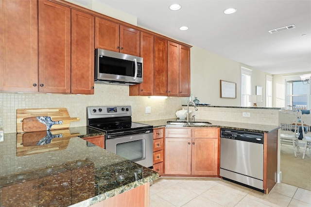 kitchen featuring visible vents, dark stone counters, appliances with stainless steel finishes, a peninsula, and a sink