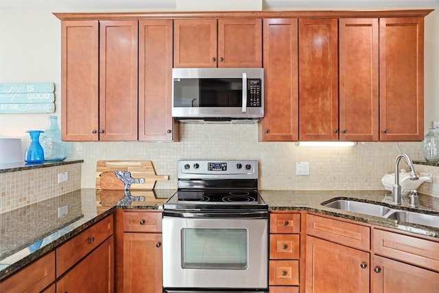 kitchen featuring a sink, dark stone countertops, tasteful backsplash, and stainless steel appliances