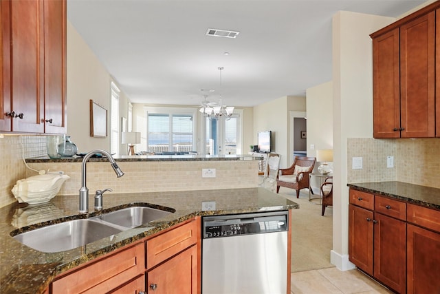 kitchen with stainless steel dishwasher, dark stone countertops, visible vents, and a sink