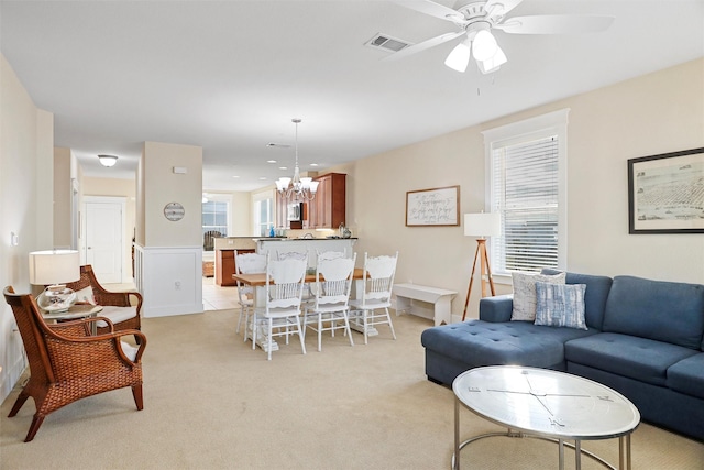 living area featuring visible vents, light carpet, and ceiling fan with notable chandelier