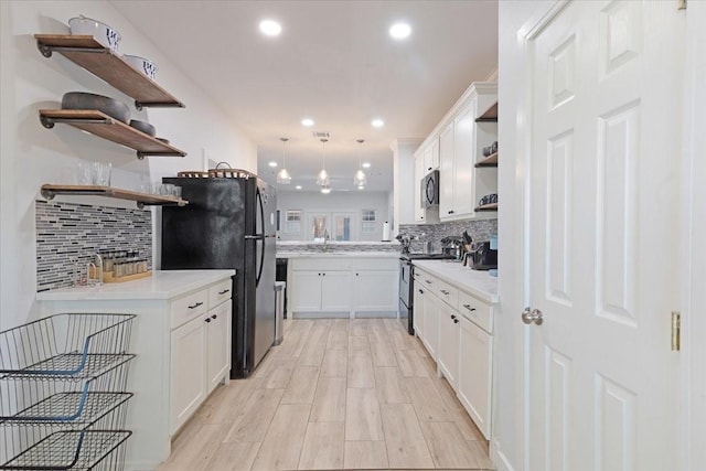 kitchen with open shelves, freestanding refrigerator, a sink, stainless steel range with electric cooktop, and white cabinets