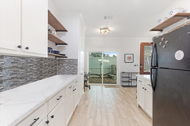 kitchen featuring visible vents, decorative backsplash, freestanding refrigerator, white cabinetry, and open shelves