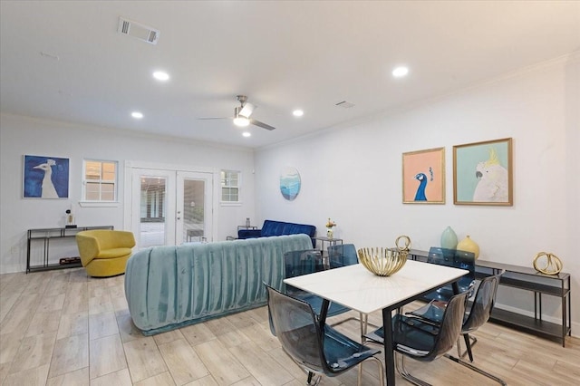 dining space with french doors, visible vents, crown molding, and light wood finished floors