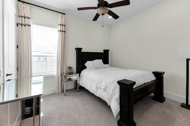 bedroom featuring baseboards, light colored carpet, and a ceiling fan