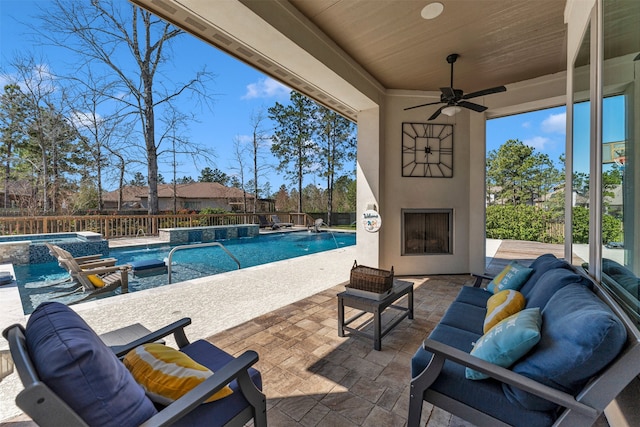 view of patio with an outdoor living space with a fireplace, a fenced backyard, a ceiling fan, and a pool with connected hot tub