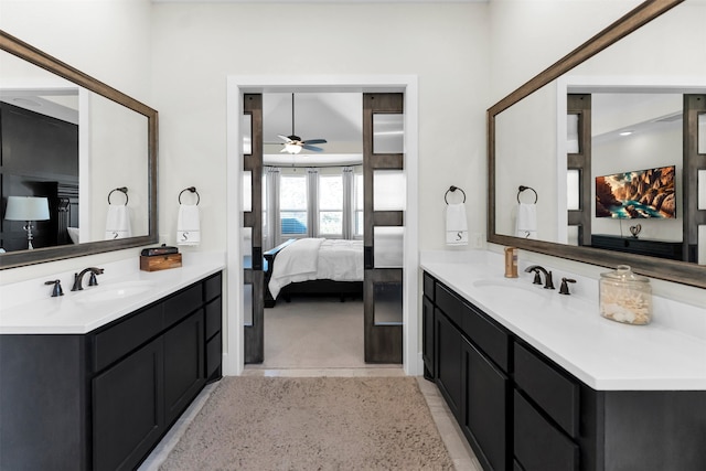 full bathroom featuring two vanities, a ceiling fan, ensuite bathroom, and a sink