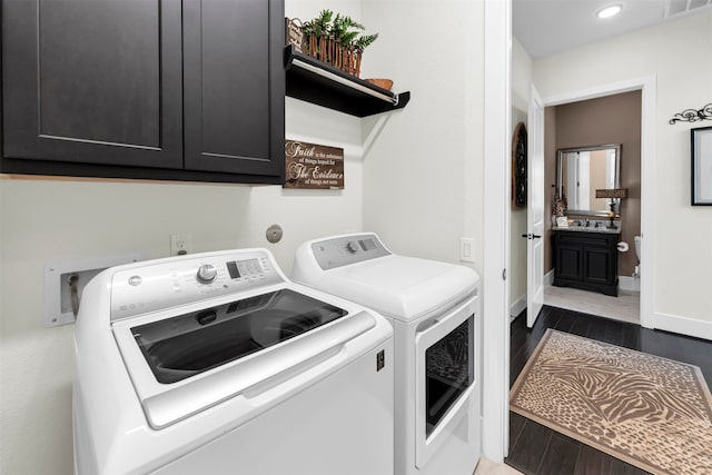 clothes washing area with visible vents, baseboards, washer and dryer, wood finished floors, and cabinet space