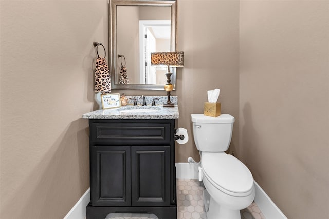 bathroom featuring toilet, vanity, and baseboards