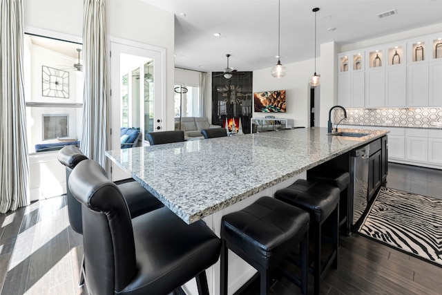 kitchen featuring tasteful backsplash, visible vents, ceiling fan, white cabinetry, and a sink