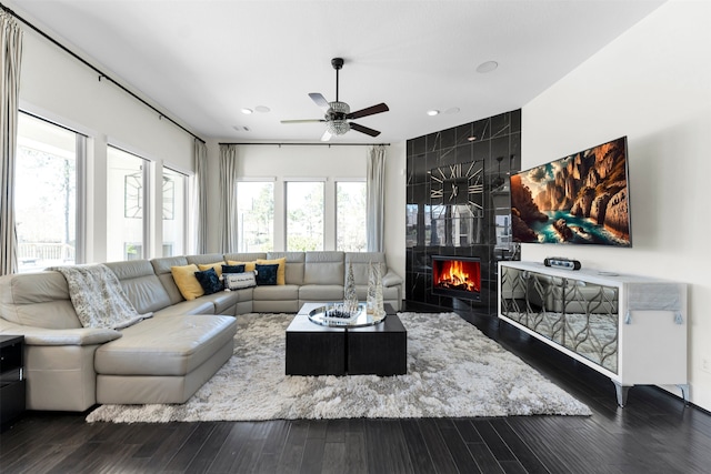 living area with a high end fireplace, plenty of natural light, wood finished floors, and a ceiling fan