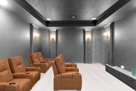 carpeted cinema featuring a raised ceiling and decorative columns