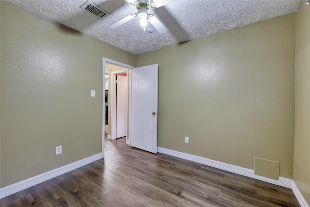 spare room featuring visible vents, a textured ceiling, dark wood finished floors, baseboards, and ceiling fan