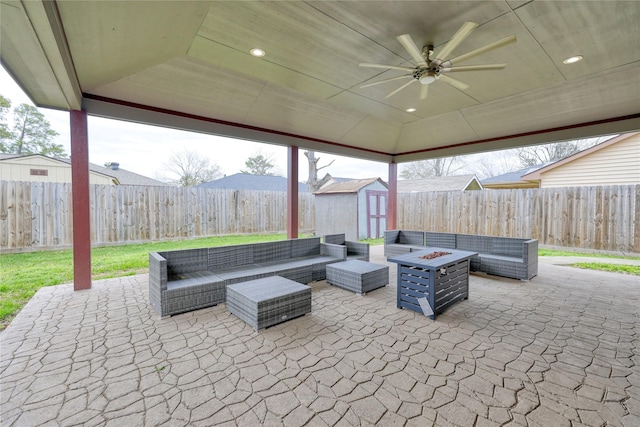 view of patio with an outbuilding, a storage shed, an outdoor living space with a fire pit, and a ceiling fan