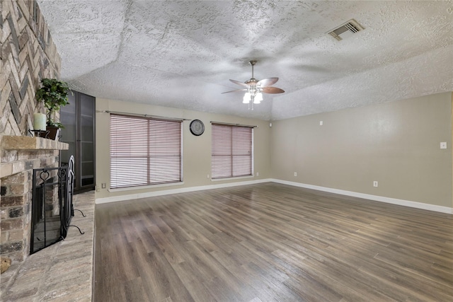 unfurnished living room with visible vents, baseboards, a textured ceiling, a brick fireplace, and light wood-type flooring