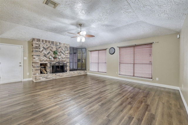 unfurnished living room with visible vents, a textured ceiling, wood finished floors, and a fireplace